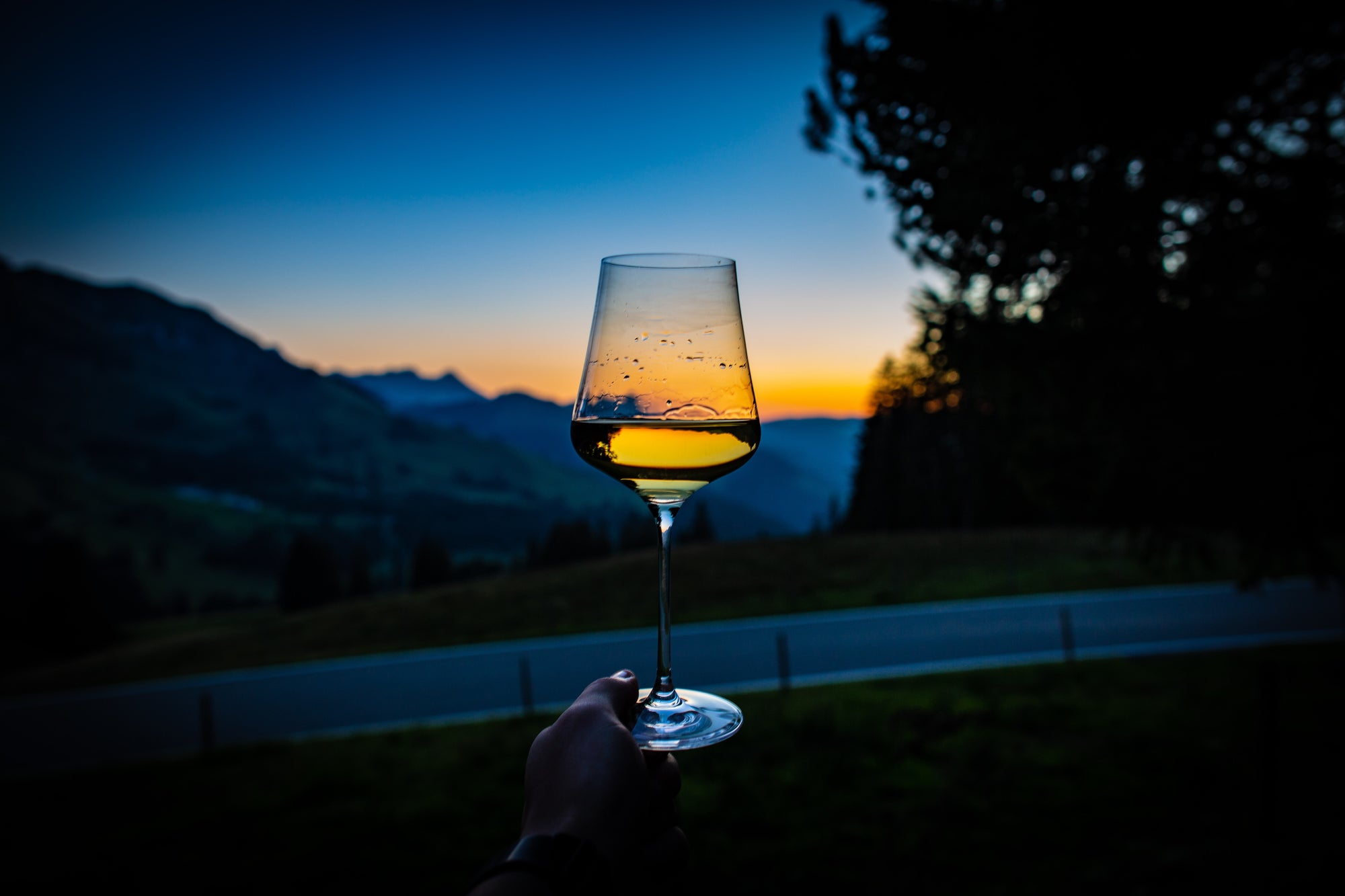 Glass of white wine on a balcony with sunset in the background